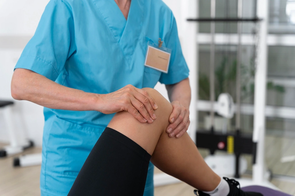 Healthcare professional examining a patient's knee during a physiotherapy session.